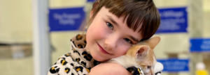 Little girl, Natalie, cuddles orange and white kitten, Tucker.